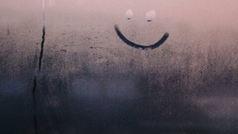 Image of a small smiley face drawn into the condensation on a window.