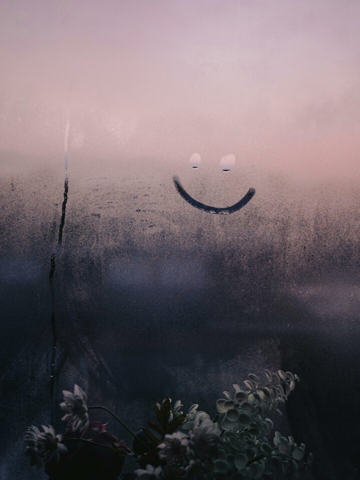 Image of a small smiley face drawn into the condensation on a window.